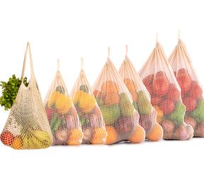 An assortment of five string bags, each filled with fresh produce