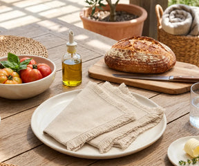 Set of natural cotton dinner napkins with decorative hemstitch detailing and fringed edges displayed in an overlapping arrangement