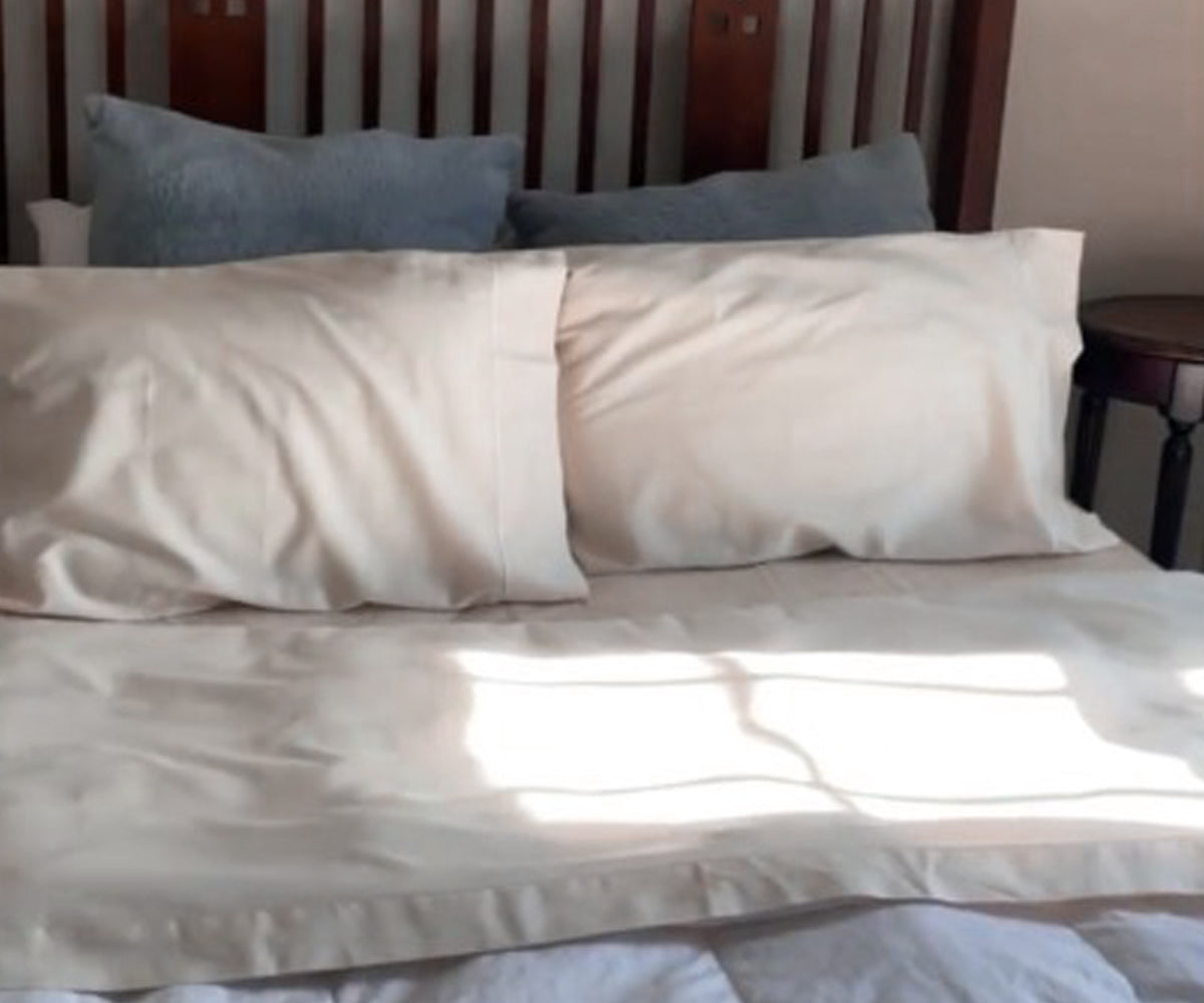 Bed arrangement with two pillows and a cotton fitted sheet