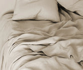 Natural linen sheet set in neutral tone, includes flat sheet, fitted sheet with 100% European flax with deep pockets, and pillowcases – displayed on a neatly made bed.