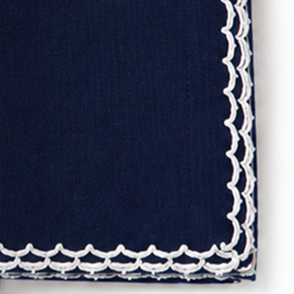 Close-up of a navy blue cotton napkin featuring a white scalloped embroidered edge.