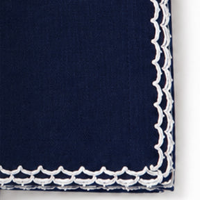Close-up of a navy blue cotton napkin featuring a white scalloped embroidered edge.