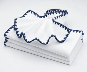 White cotton embroidered napkins with navy blue trim – classic cloth napkins for elegant table settings.