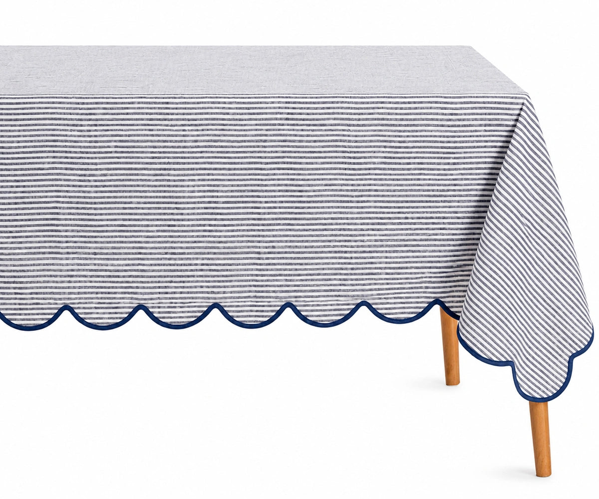 Navy blue and white thin striped linen tablecloth with a decorative navy scalloped edge draped over a table.
