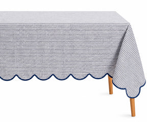 Navy blue and white thin striped linen tablecloth with a decorative navy scalloped edge draped over a table.