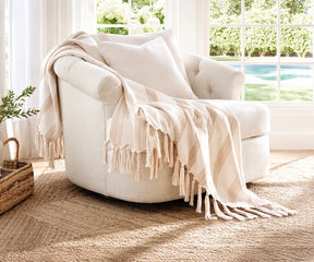Cotton throw with fringe styled on a lounge chair creating a relaxed and inviting home decor look