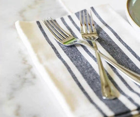 A set of six restaurant napkins with blue and white stripes arranged on a plate