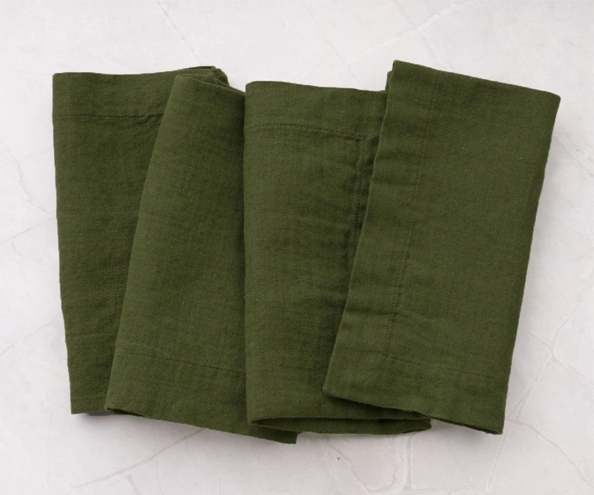 Folded olive green cotton linen napkins with minimalist solid design, reusable dinner napkins