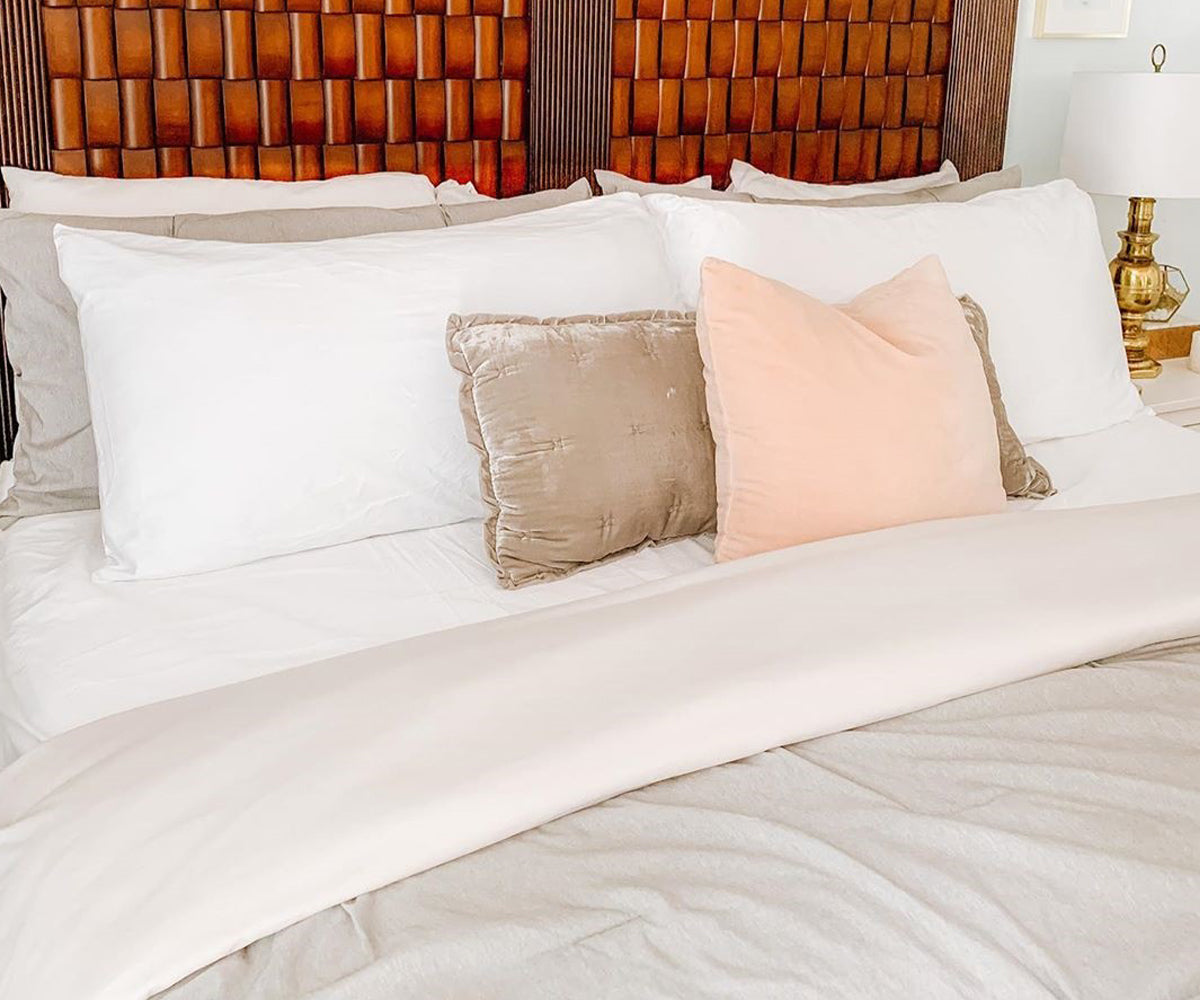 Bed dressed with white cotton fitted sheets and pillows