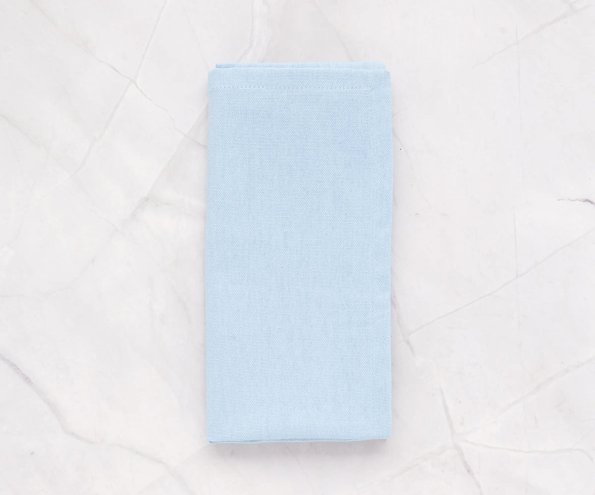 Pale blue cotton napkins neatly folded on a dining table