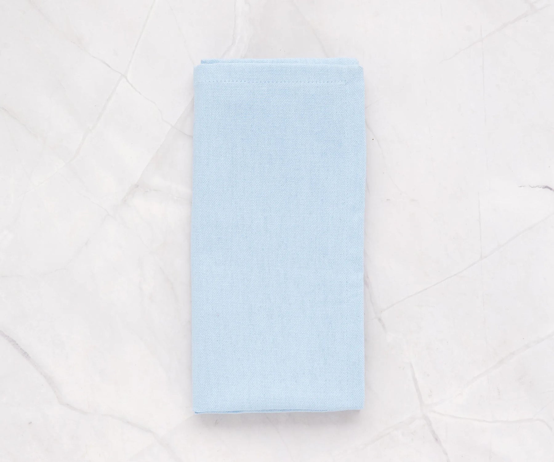 Pale blue cotton napkins neatly folded on a dining table