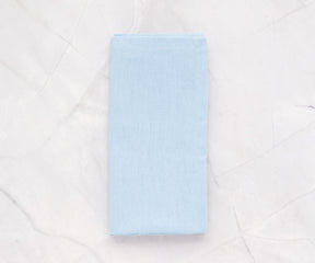 Pale blue cotton napkins neatly folded on a dining table