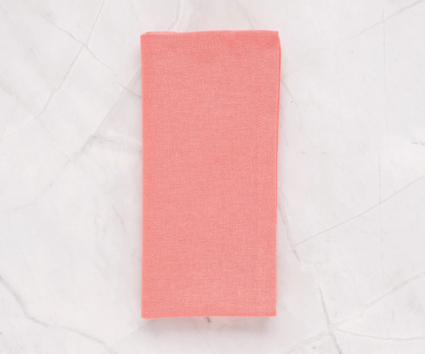 Set of 12 pink cotton napkins in 100% cotton, neatly folded on a dining table with a matching pink cotton tablecloth.