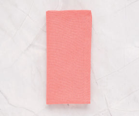 Set of 12 pink cotton napkins in 100% cotton, neatly folded on a dining table with a matching pink cotton tablecloth.