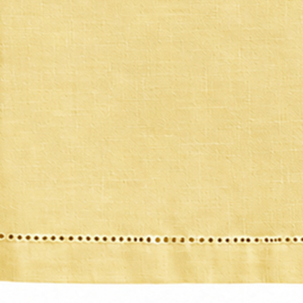 A close-up of a butter yellow fabric with a horizontal row of decorative eyelet embroidery along the bottom edge.