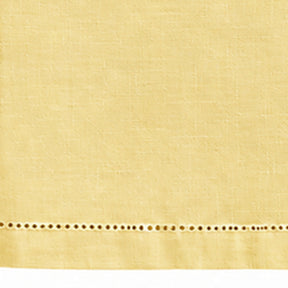 A close-up of a butter yellow fabric with a horizontal row of decorative eyelet embroidery along the bottom edge.