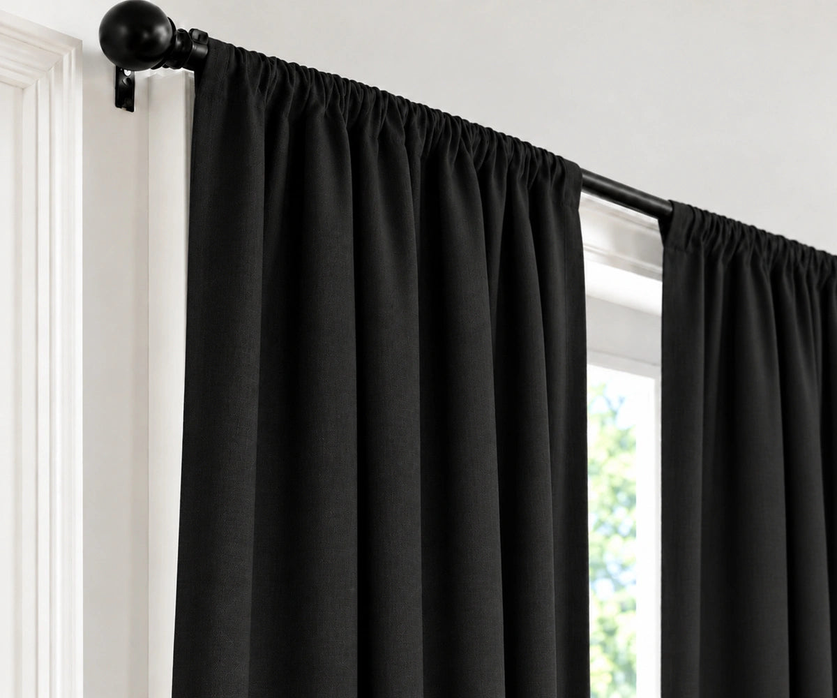 Black curtain panels hanging from a black rod in a window, shown against a white wall and trim.