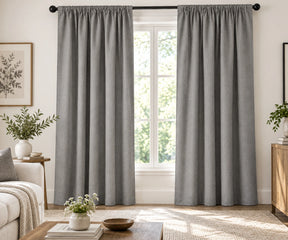 Pair of cloud plain cotton curtains hanging on a dark rod in a bright living room.