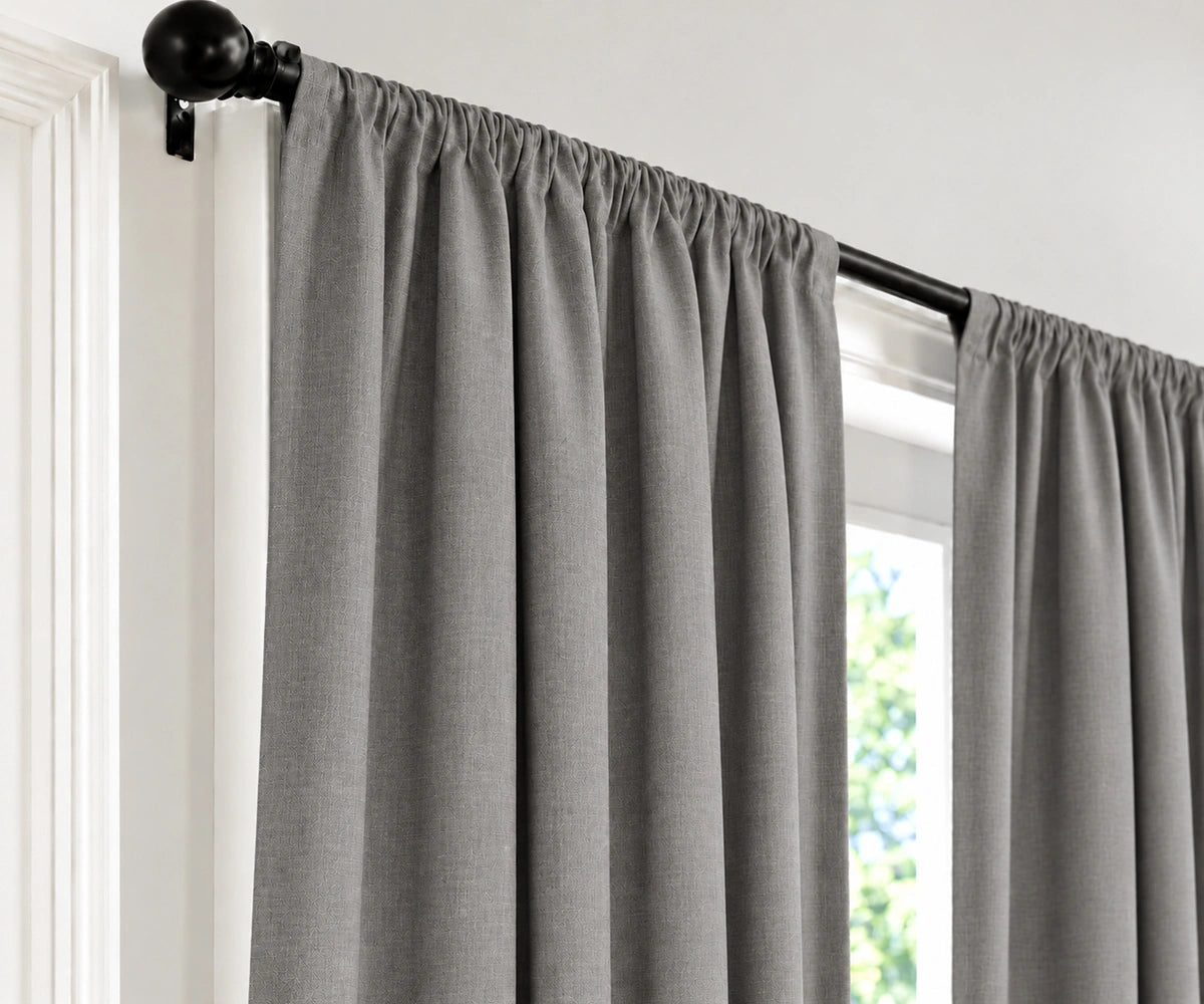 Gray cloud panels hanging from a black rod in a window, shown against a white wall and door frame.
