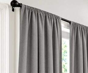 Gray cloud panels hanging from a black rod in a window, shown against a white wall and door frame.