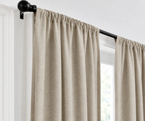 Plain cotton flax beige curtains gathered on a dark metal curtain rod
