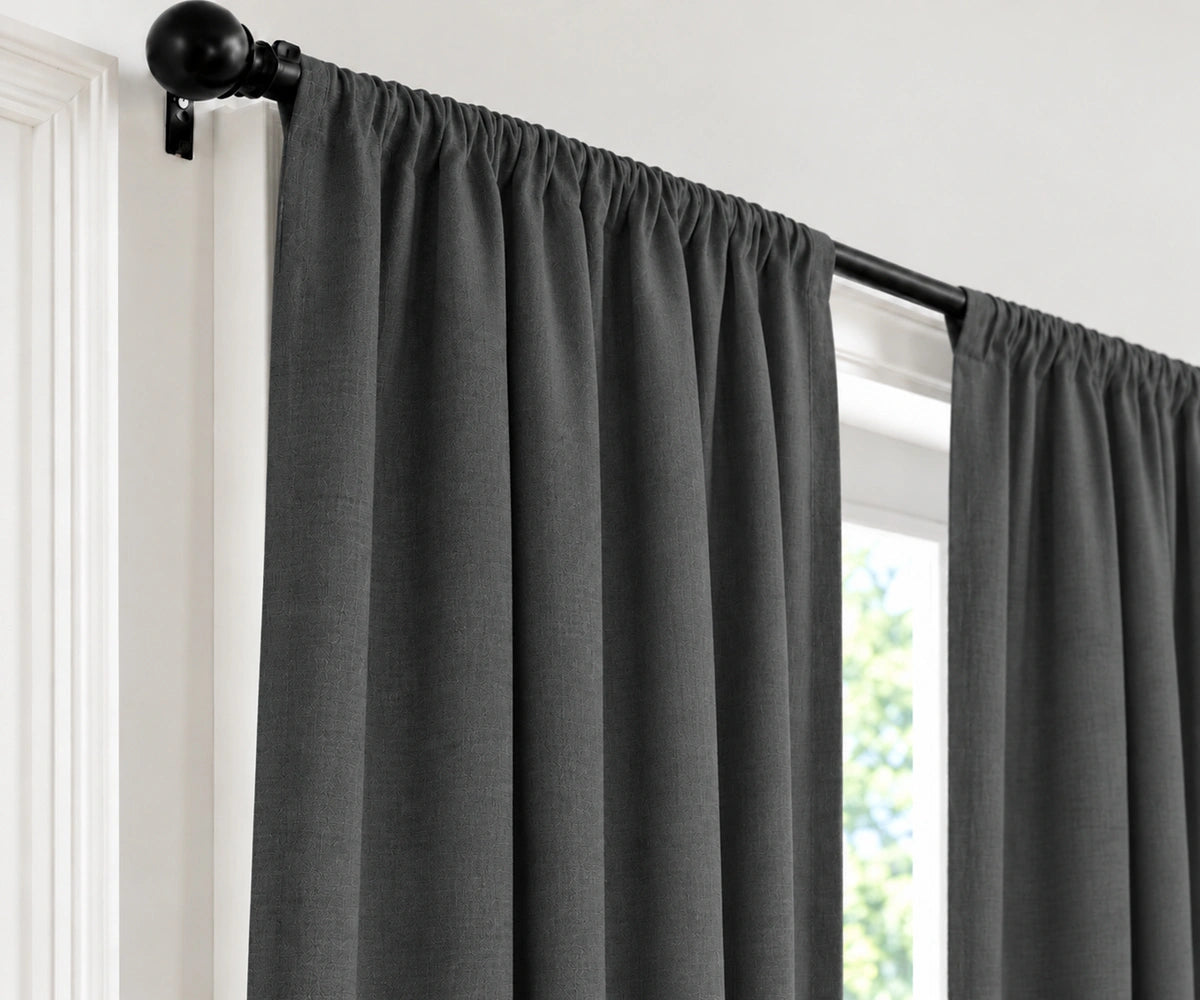 Dark gray curtain panels hanging from a black rod with decorative finials, shown installed on a window in a white interior setting.