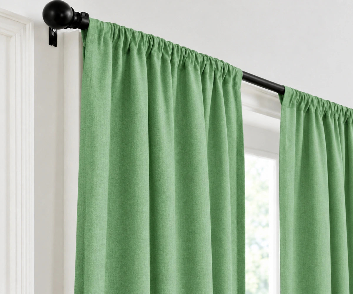 A hunter green curtain panel hanging from a black rod on a white window frame.