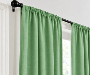 A hunter green curtain panel hanging from a black rod on a white window frame.