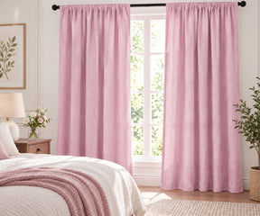 Pair of light pink plain cotton curtains hanging on a dark rod in a bright living room.