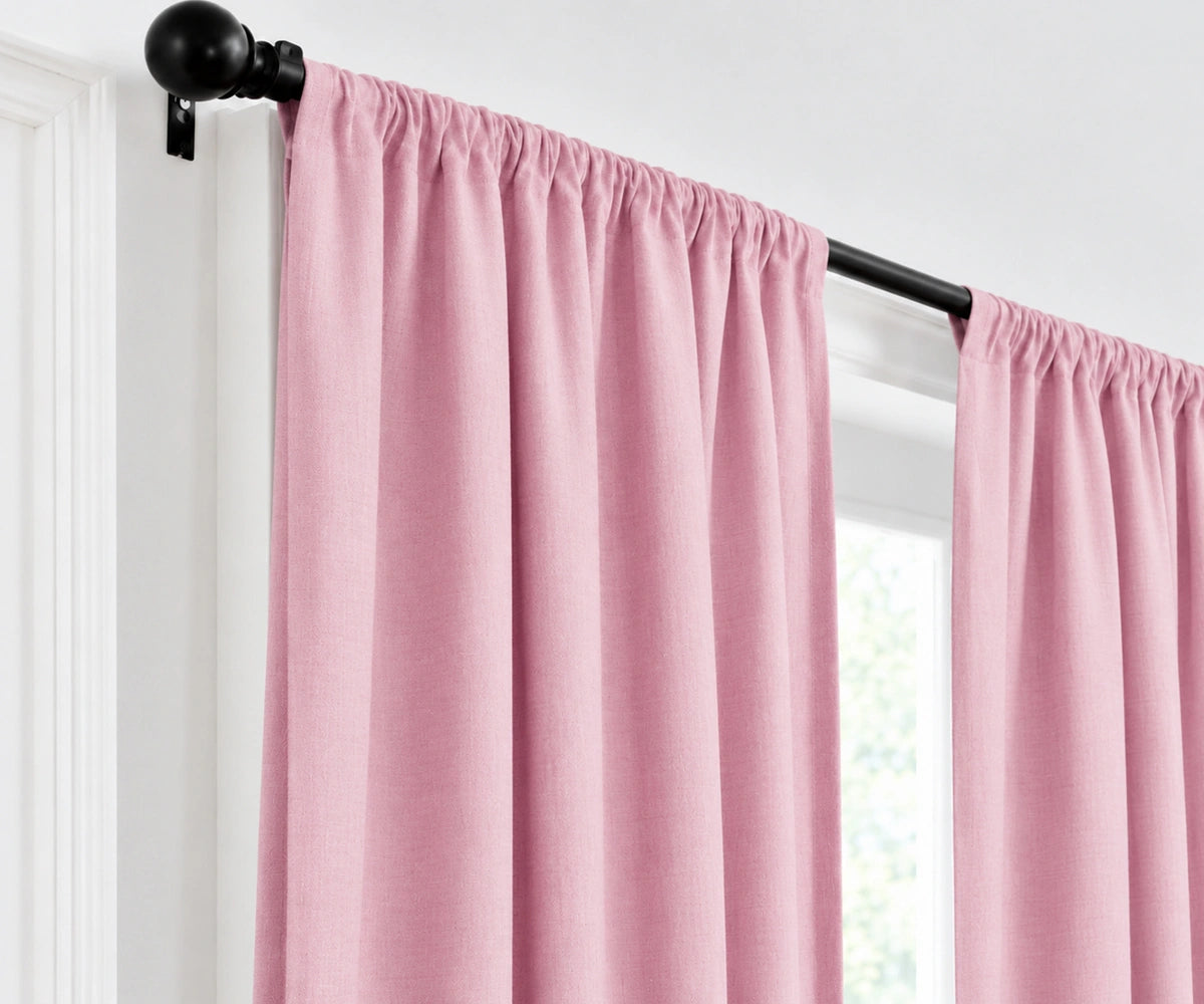 Plain cotton light pink curtains gathered on a dark metal curtain rod