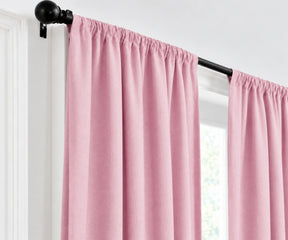 Plain cotton light pink curtains gathered on a dark metal curtain rod
