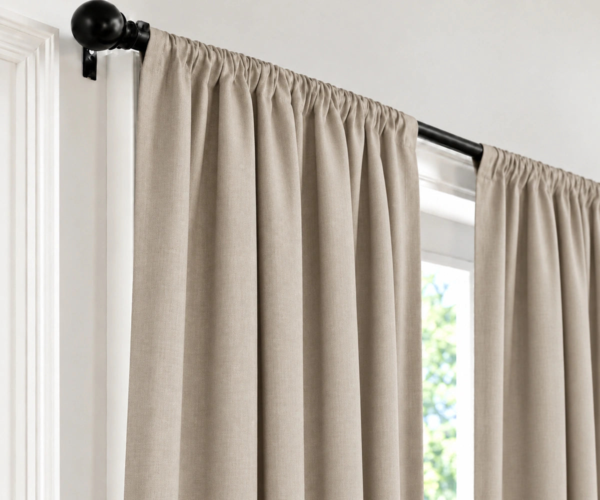 Natural plain cotton drapes mounted on a dark curtain rod in a brightly lit room.