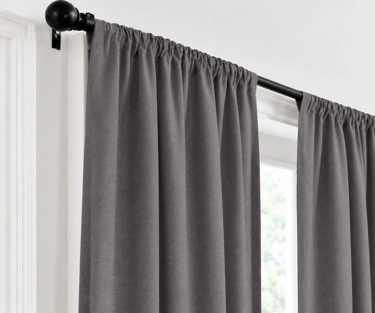 A storm curtain panel hanging from a black rod in a window, shown against a white wall and trim.