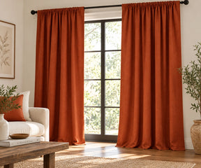 Pair of terracotta plain cotton curtains hanging on a dark rod in a bright living room.