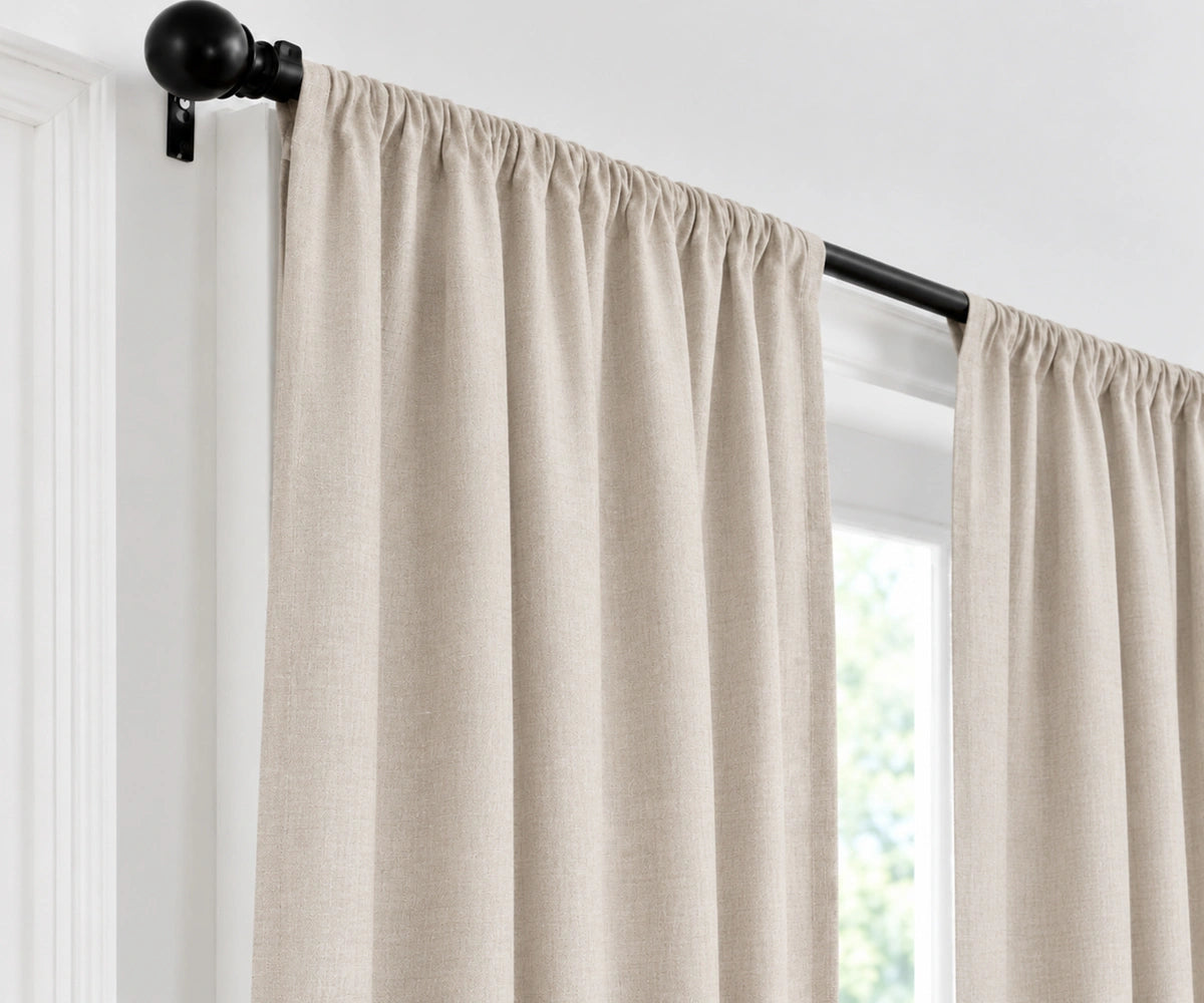 vintage blush curtain panels hanging from a black rod in a bright room with white walls and a window.