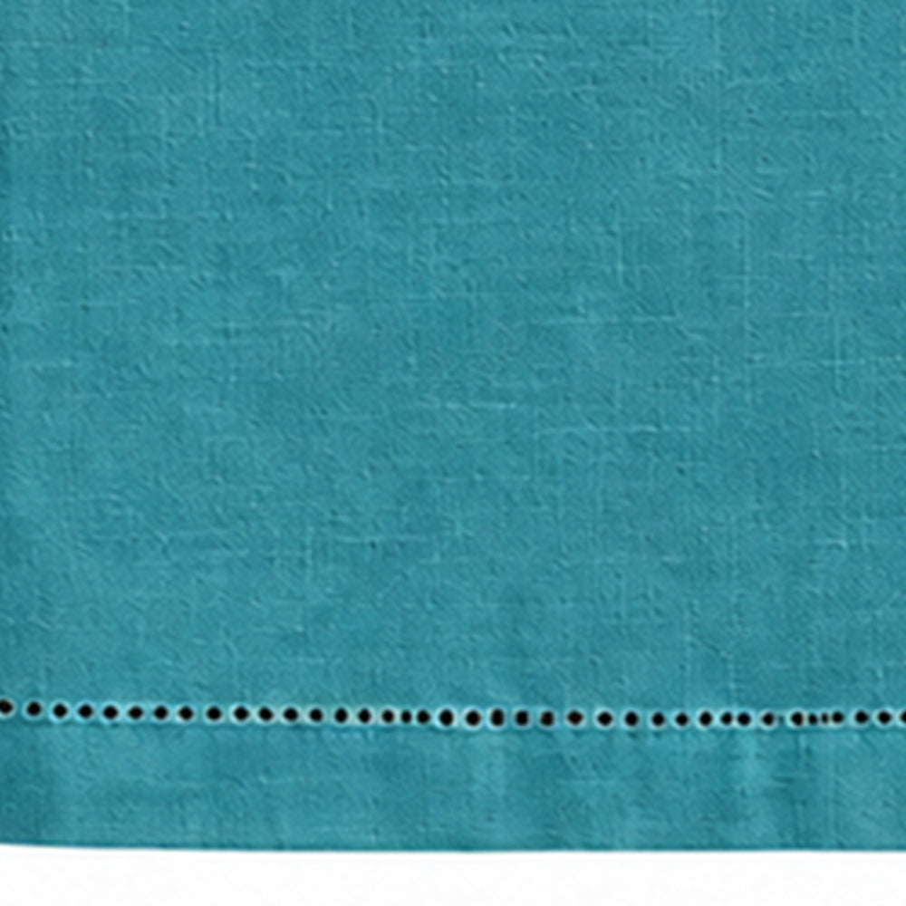 Close-up of a plain teal cotton linen tablecloth showing hemstitch border detailing.