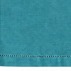Close-up of a plain teal cotton linen tablecloth showing hemstitch border detailing.