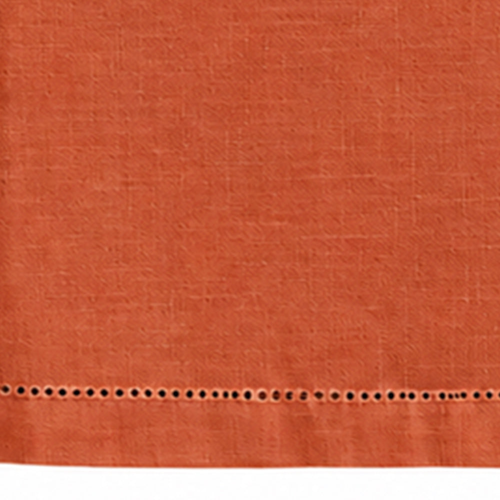 Close-up of a plain terracotta cotton linen tablecloth showing hemstitch border detailing.