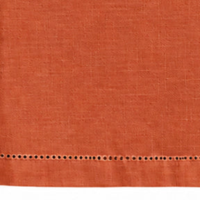 Close-up of a plain terracotta cotton linen tablecloth showing hemstitch border detailing.