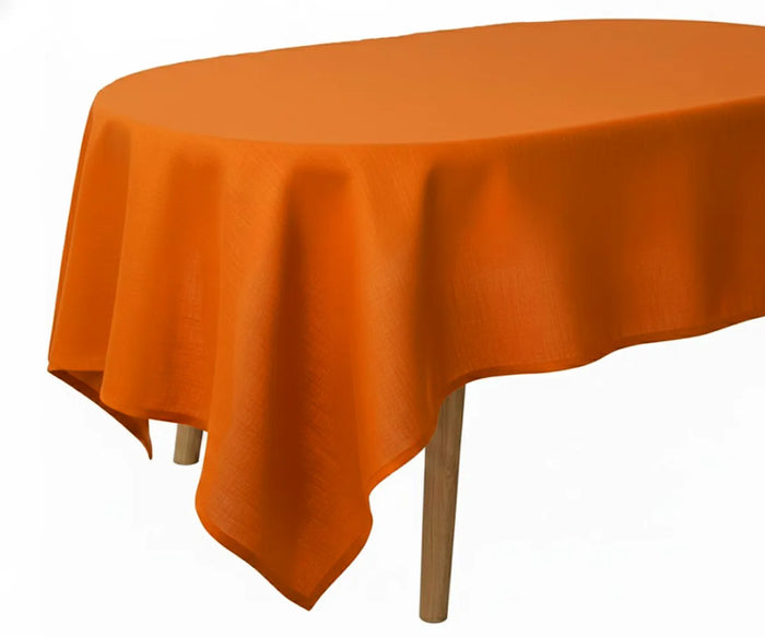 Orange oval linen tablecloth on a round table with wooden legs against a white background.