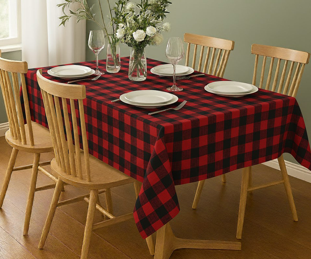 Dining table set with a red and black checkered tablecloth, plates, and glasses.