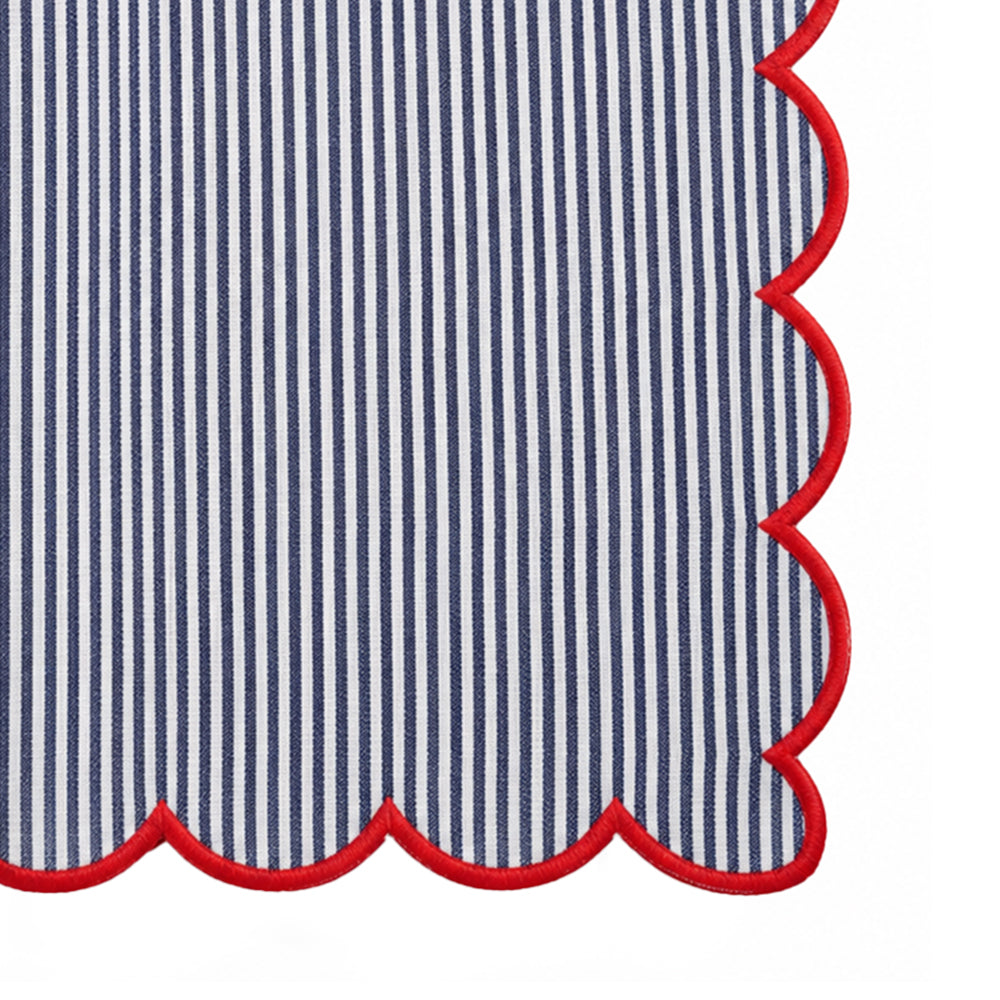 Close-up of a striped textile with narrow vertical navy and white stripes and a scalloped edge outlined in red.
