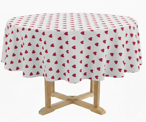 White round tablecloth covered with small red heart patterns, draped over a wooden pedestal table, displayed in a media gallery with a pattern thumbnail preview on the right