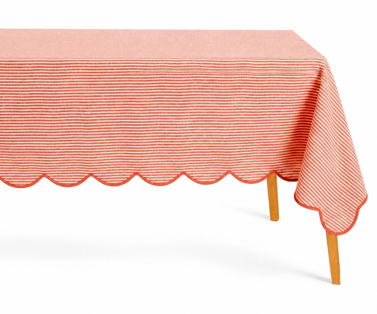 Red and white thin striped linen tablecloth with a decorative red scalloped edge draped over a table.
