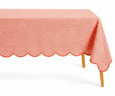 Red and white thin striped linen tablecloth with a decorative red scalloped edge draped over a table.