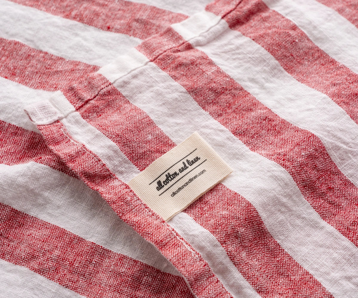 Red and white striped linen kitchen towel close up with linen label detail, textured fabric