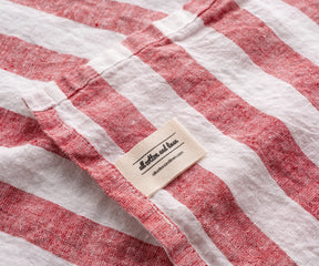 Red and white striped linen kitchen towel close up with linen label detail, textured fabric