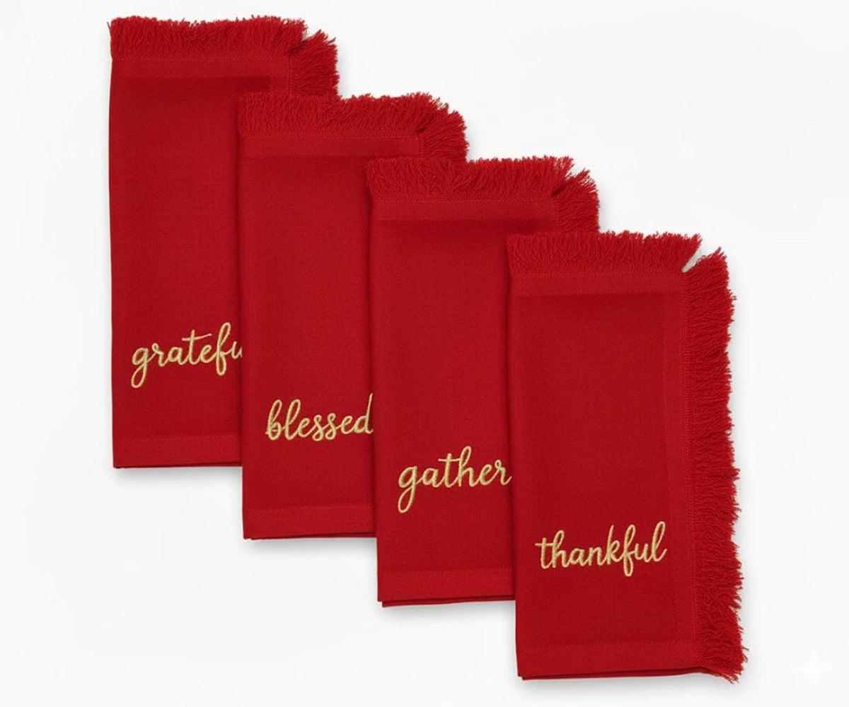 Festive red embroidered napkins with gold lettering and fringed edges for elegant dining