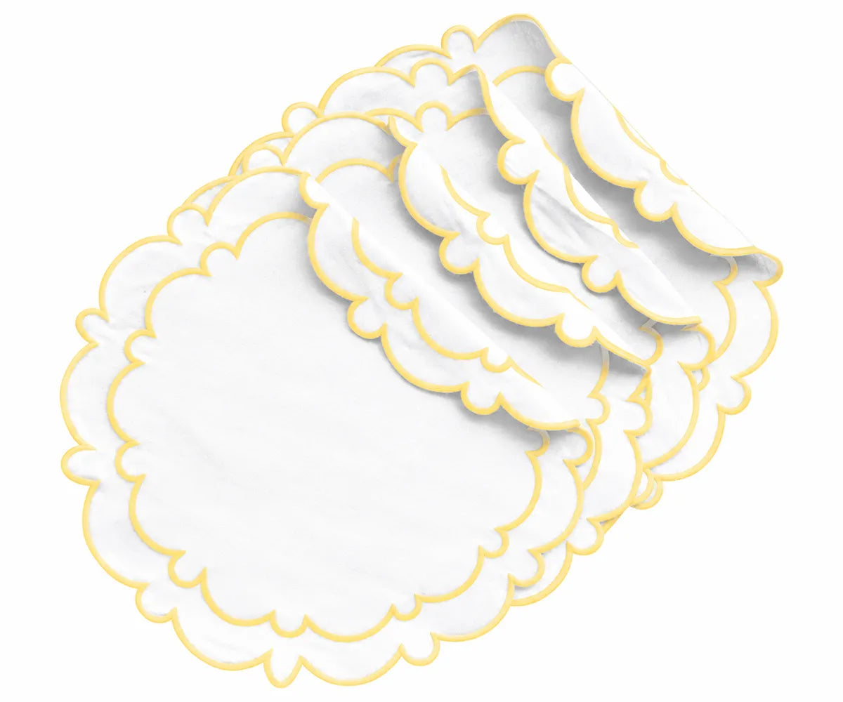 White and butter yellow round cotton placemats with scalloped edges styled on a dining table with neutral dinnerware.