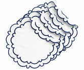 Round navy blue cotton placemats with white centers and scalloped navy blue edges, arranged in a layered stack for a classic dining table setting.